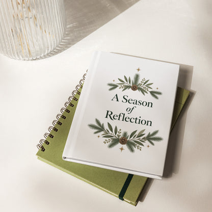 A Season of Reflection botanical hardcover journal resting on green notebooks beside a ribbed glass vase.