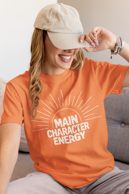 Woman wearing a burnt orange 'Main Character Energy' garment-dyed tee with sunburst graphic."