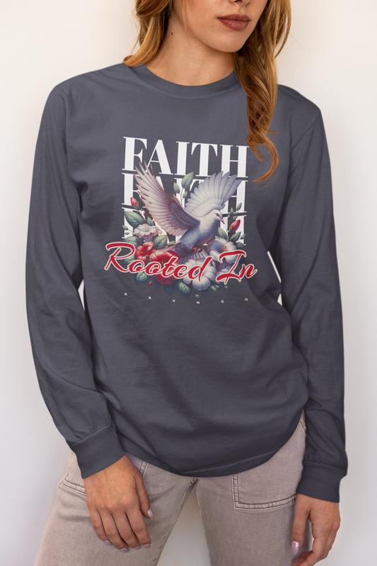 A woman wearing a dark gray long-sleeve graphic t-shirt with a white dove, red roses, and the text 'FAITH ROOTED IN' on the front, paired with light beige pants.