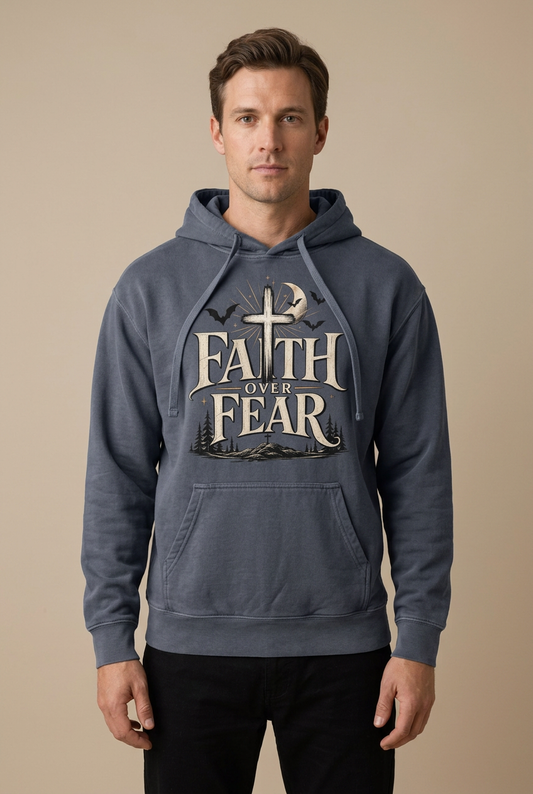 Male model wearing a Denim hoodie with cream ‘Faith Over Fear’ lettering, a cross, crescent moon, bats, and woodland silhouettes.