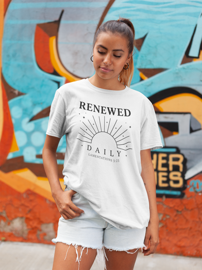 Woman wearing a white t-shirt with 'RENEWED DAILY' text in front of a colorful mural.