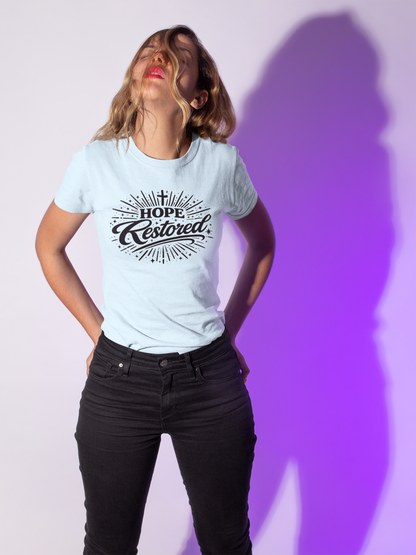 Woman wearing a light blue t-shirt with 'Hope Restored' text against a white and purple gradient background