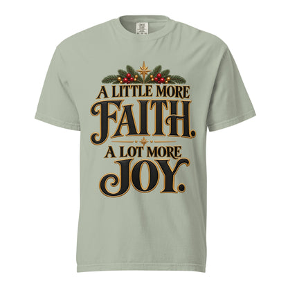 A Little More Faith, A Lot More Joy” Christmas tee with black-and-gold lettering, festive greenery, red berries, and gold stars.