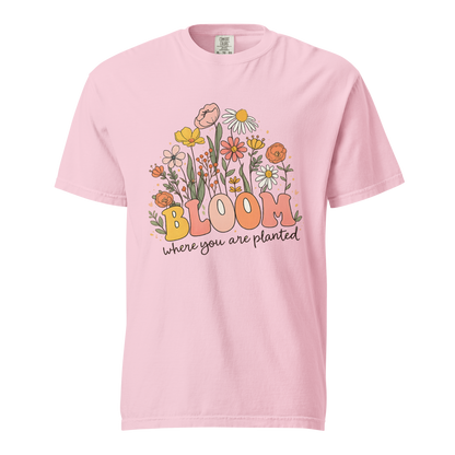 Flat mockup of a pink 'Bloom Where You Are Planted' garment-dyed tee with wildflower garden graphic.