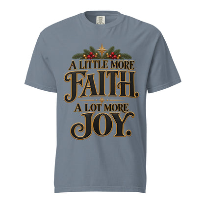 A Little More Faith, A Lot More Joy” Christmas tee with black-and-gold lettering, festive greenery, red berries, and gold stars.