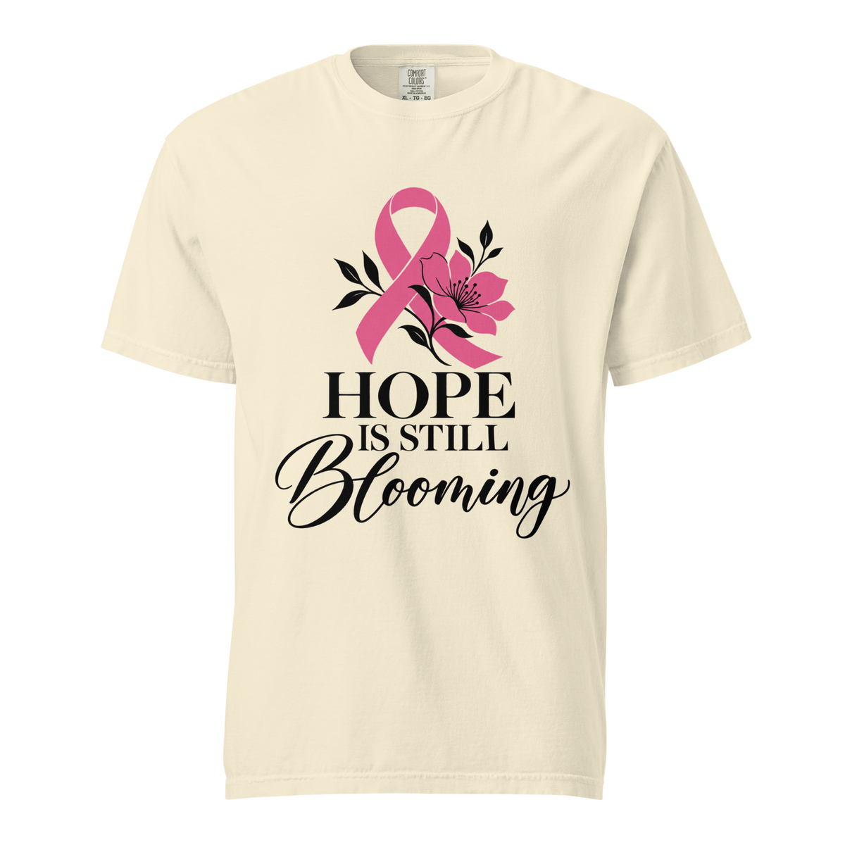 Ivory garment-dyed T-shirt with pink ribbon and floral artwork reading “Hope Is Still Blooming,” front view.