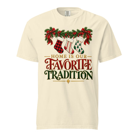 Front view of an Ivory “Home Is Our Favorite Tradition” Christmas tee with three patterned stockings, evergreen garland, red bows, and red-and-green lettering.