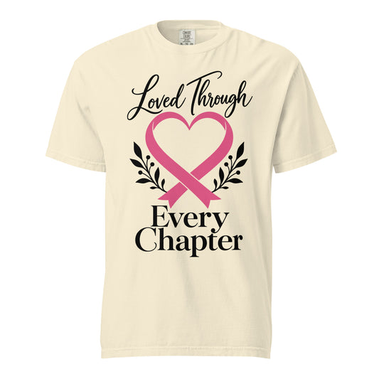 Ivory tee with a pink heart-shaped ribbon, black botanical sprigs, and “Loved Through Every Chapter” lettering.