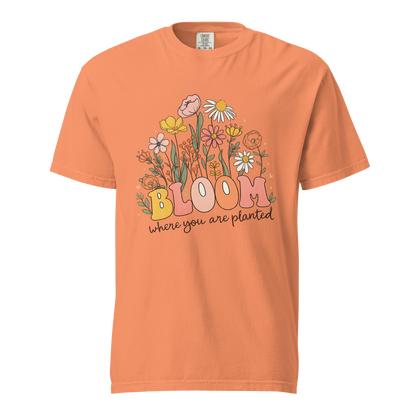 Flat mockup of a orange 'Bloom Where You Are Planted' garment-dyed tee with wildflower garden graphic.