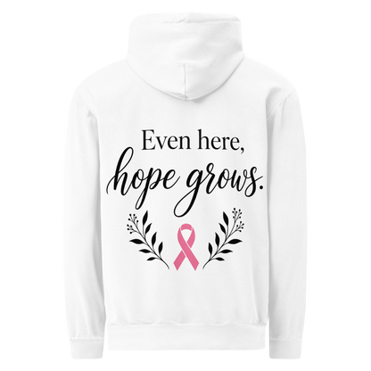 White hoodie back with black “Even here, hope grows.” lettering, a pink awareness ribbon, and botanical sprigs