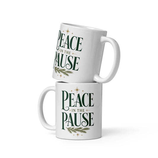 Two white Peace in the Pause ceramic mugs stacked together, featuring forest-green lettering, gold stars, and an evergreen sprig.